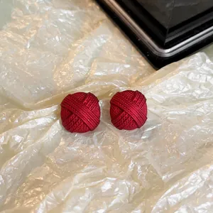 Gros plan sur d'élégantes boucles d'oreilles clous nœud rouge à texture tressée fine