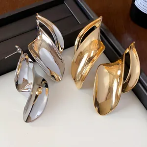 Detail van onregelmatige metalen oorknopjes in bladvorm in goud en zilver