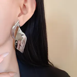 Close-up van een model met grote onregelmatige zilveren metalen oorbellen