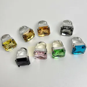 Primo piano di vari anelli con grandi cristalli a taglio quadrato in colori vivaci e argento.