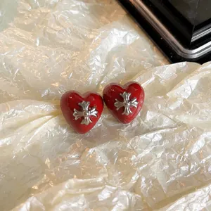 Vue détaillée des boucles d'oreilles en forme de cœur rouge avec croix argentée