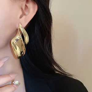 Detail van model met onregelmatige gouden bladmetaal oorknopjes met glanzende afwerking