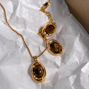 Detail shot of gold-plated jewelry set with imitation tiger eye stones on white paper