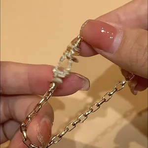 Close-up detail of a gold-plated chain bracelet with a sparkling zircon horseshoe charm.