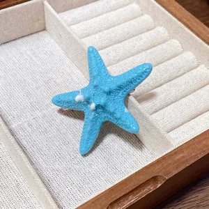 Ocean-inspired blue acrylic starfish hair clip placed in a wooden jewelry organizer