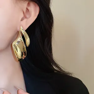 Detailopname van onregelmatige gouden blad oorbellen gedragen door een mooi model