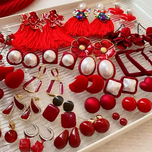 Vue détaillée de boucles d'oreilles rouges variées avec pompons et perles.