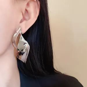 Close-up van onregelmatige zilveren metalen bladoorbellen aan het oor van het model