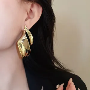 Gedetailleerde close-up van elegante gouden bladmetalen oorknopjes gedragen door een model
