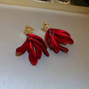 Gros plan de boucles d'oreilles pétales rouges avec clous carrés dorés texturés