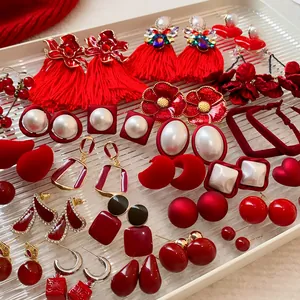Gros plan de diverses boucles d'oreilles rouges vintage avec glands, fleurs et clous en cœur.