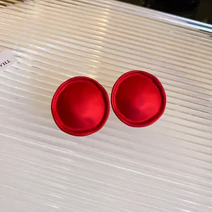 Gros plan macro de boucles d'oreilles rondes rouge mat sur fond de verre cannelé