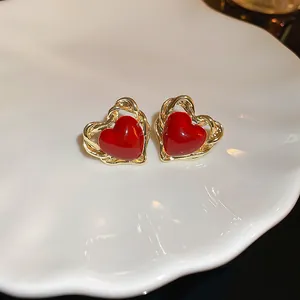 Gros plan de boucles d'oreilles cœur rouge élégantes avec bordure dorée torsadée