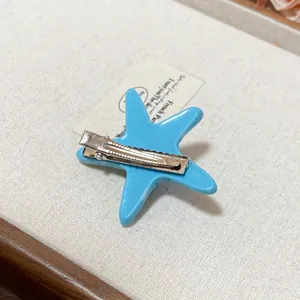 Detailed view of the back of a blue acrylic starfish hair clip with metal clip