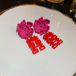 Vue macro de boucles d'oreilles fleurs magenta avec des breloques rouges translucides