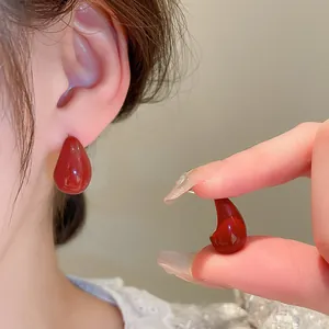 Élégantes boucles d'oreilles clous rouges en goutte, vue détaillée et portée sur l'oreille.