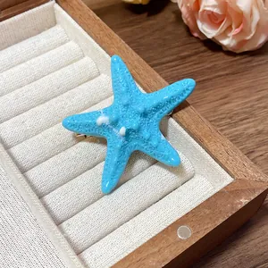 Close-up view of a light blue acrylic starfish hair clip in a wooden jewelry box.