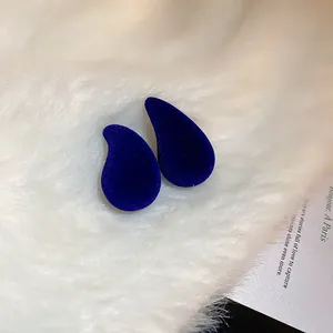 Vue détaillée des boucles d'oreilles en velours bleu sur fond de fourrure blanche