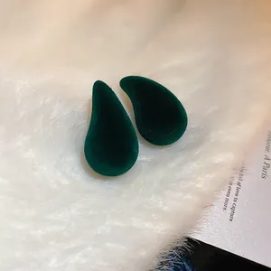 Élégantes boucles d'oreilles en velours vert foncé sur fond de fausse fourrure.