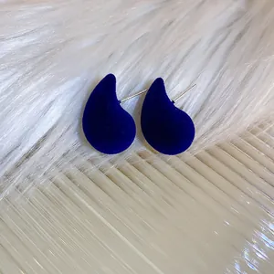 Vue macro détaillée d'élégantes boucles d'oreilles en velours bleu foncé sur fausse fourrure