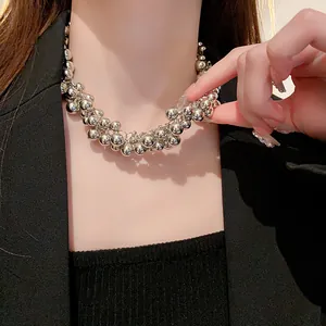 Close-up detail of a bold clustered silver ball necklace worn with a black outfit