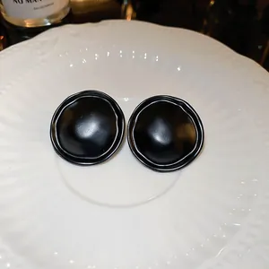 Vue détaillée de boucles d'oreilles rondes noir mat vintage sur une assiette