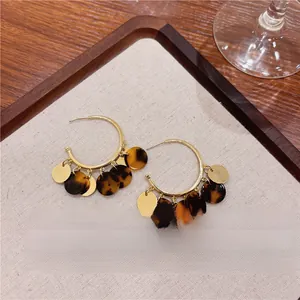 Close-up detail of retro tortoiseshell tassel hoop earrings with elegant gold-tone metallic accents.