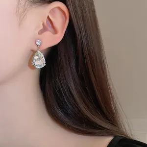 Detaillierte Makroaufnahme eines eleganten silbernen Kristall-Ohrrings am Modell.