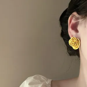 Detaillierte Nahaufnahme von eleganten Vintage-Goldrosen-Ohrsteckern an einem Modell