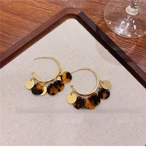 Close-up view of vintage hoop earrings featuring dark tortoise shell tassel charms