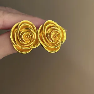 Makroaufnahme von goldenen Vintage-Rosenohrsteckern mit eleganten und feinen Blattdetails.