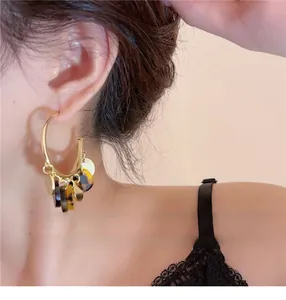 Close-up of stylish tortoiseshell fringe hoop earrings on model for design detail view