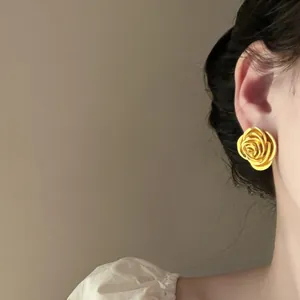 Nahaufnahme eines Modells, das elegante goldene Vintage-Rosenohrstecker mit mattem Finish trägt