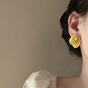 Detailansicht eleganter goldfarbener Vintage-Rosen-Ohrstecker, getragen von einem Model