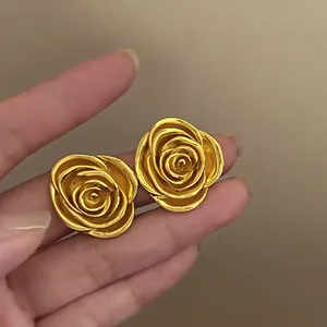 Nahaufnahme goldener Vintage-Ohrstecker in Rosenform mit detaillierten Blütenblättern