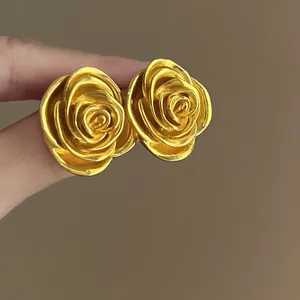 Nahaufnahme von goldenen Rosen-Ohrsteckern im Vintage-Stil mit reliefierten Blüten.