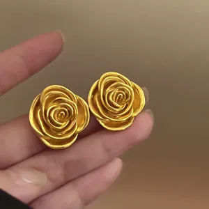 Elegante goldfarbene Rosenblüten-Ohrstecker mit mattem Vintage-Finish aus der Nähe.