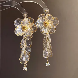 Eleganti orecchini a nappa con fiori in acrilico, bordi dorati e dettagli in strass.