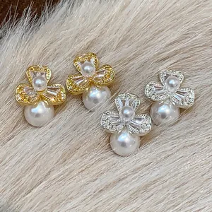 Detailed shot of elegant French-style flower zircon earrings with pearl drops on fur