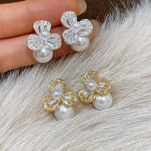 Close-up detail of elegant gold and silver zircon flower earrings with pearls on fur
