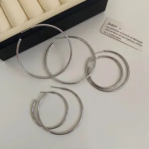 Set aus minimalistischen silbernen Creolen in verschiedenen Größen auf weißem Hintergrund
