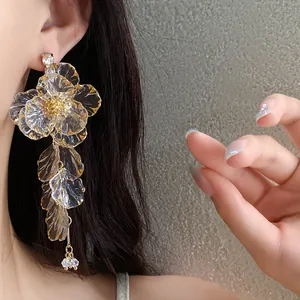 Primo piano dettagliato di eleganti orecchini a nappa con fiori in acrilico e accenti dorati