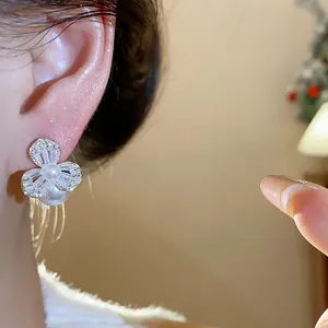 Detailed close-up shot of elegant zircon flower earring with pearl drop worn on ear