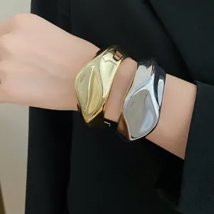 Primer plano de elegantes brazaletes metálicos irregulares con diseño arrugado en la muñeca