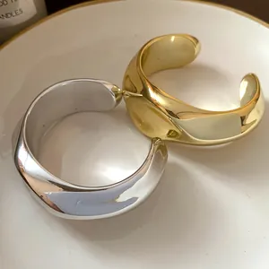 Detalle de brazaletes metálicos irregulares con textura de pliegues lisos en oro y plata