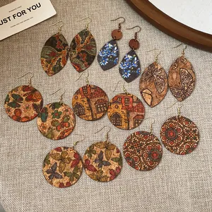 Overhead detail view of multiple printed bohemian style earrings on a textured fabric surface