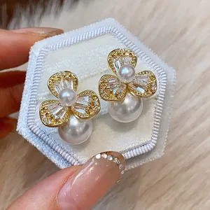 Close-up of elegant flower pearl earrings with sparkling zircons on white velvet box