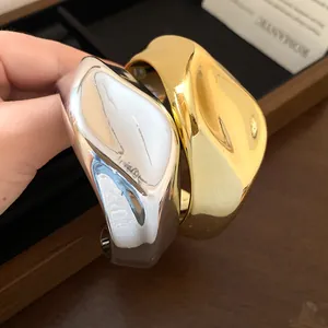 Detalle de brazaletes abiertos arrugados irregulares con acabados en oro y plata pulidos