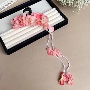 Vue détaillée de la pince à cheveux avec fleurs en tissu rose et glands perlés élégants.