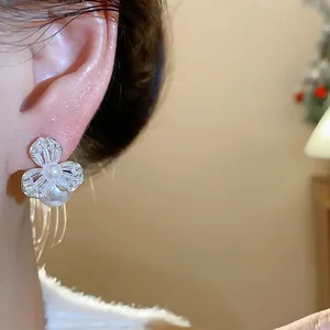 Close-up of elegant zircon flower pearl earring worn on ear with soft lighting.